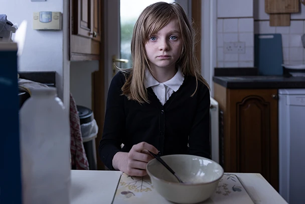 Girl sitting at table with an empty breakfast bowl