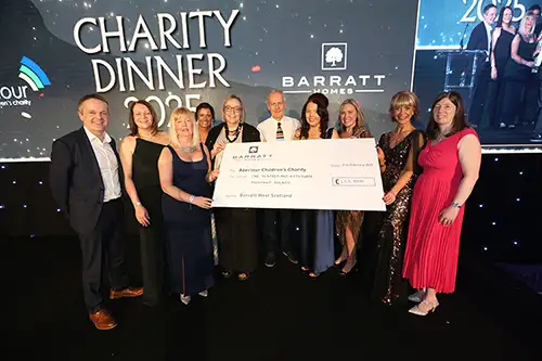 Guests and Aberlour staff at a charity fundraising dinner, holding a large cheque donation