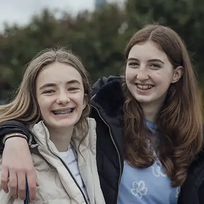 Two teenage girls smiling together outdoors