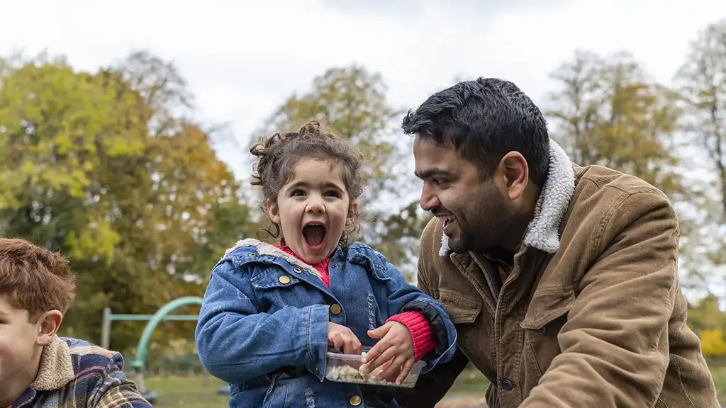 A father and daughter laughing together in a park