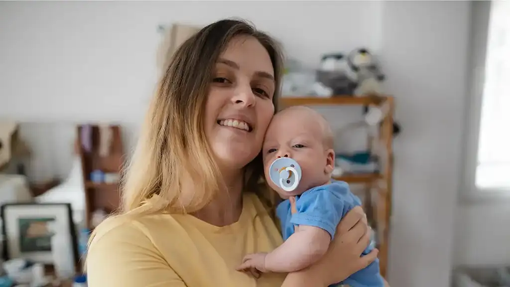 A mother smiling with her baby at home, supported by Aberlour's Mother and Child Recovery House