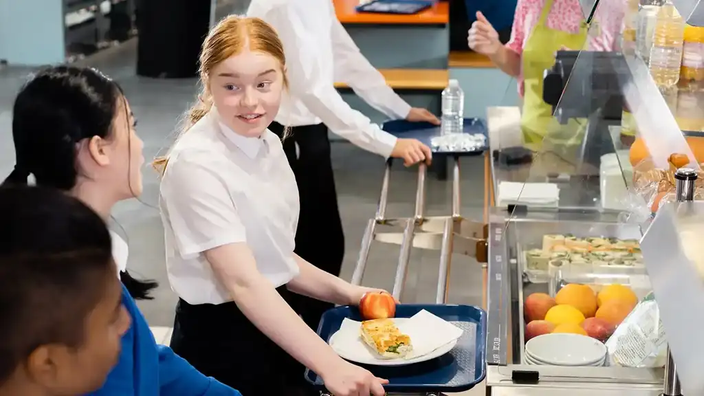 A pupil being served a meal in a school dinner hall